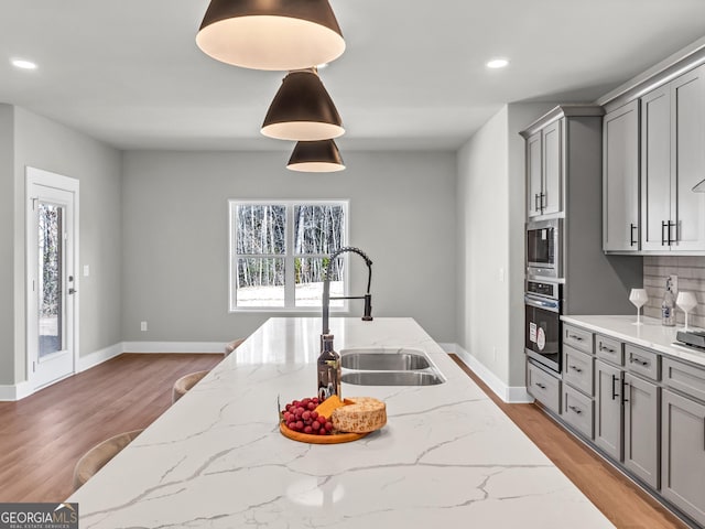 kitchen with plenty of natural light, gray cabinets, appliances with stainless steel finishes, and a sink