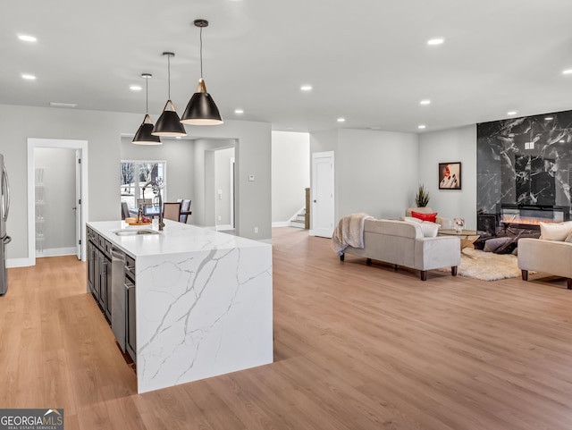 kitchen featuring pendant lighting, a sink, open floor plan, recessed lighting, and light wood-style floors