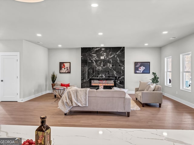 living area featuring a premium fireplace, recessed lighting, baseboards, and wood finished floors