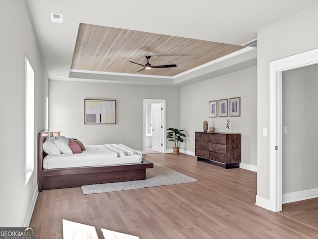 bedroom with wooden ceiling, a raised ceiling, baseboards, and wood finished floors