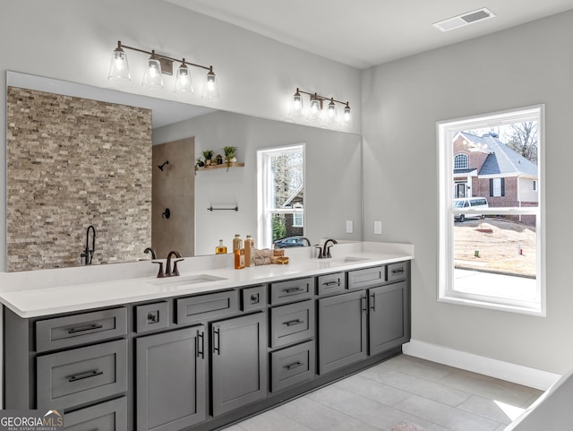 full bathroom with double vanity, visible vents, tiled shower, and a sink