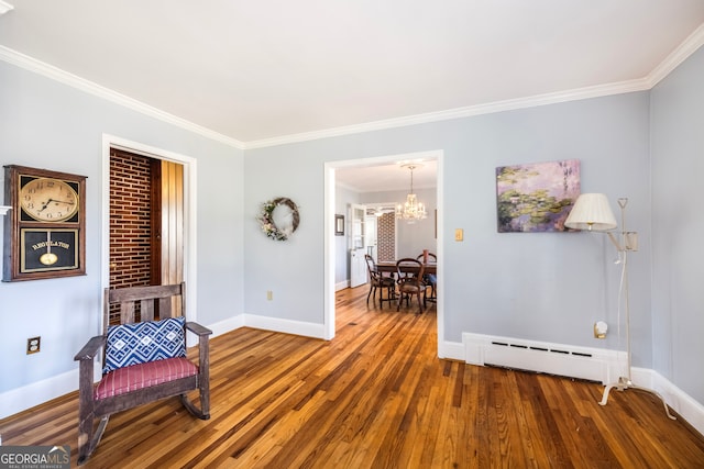 living area with a baseboard radiator, baseboards, wood finished floors, and ornamental molding