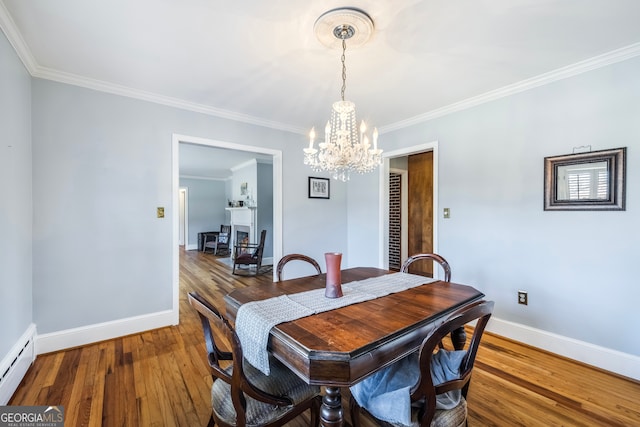 dining room featuring crown molding, baseboards, baseboard heating, wood finished floors, and a notable chandelier