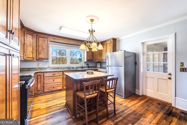 kitchen with stone countertops, freestanding refrigerator, a sink, range with electric cooktop, and crown molding