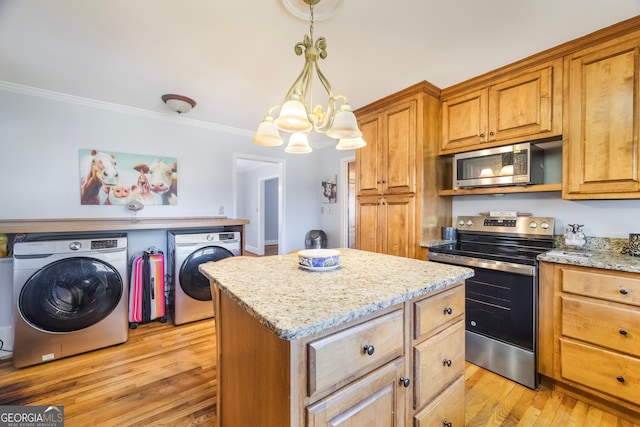 kitchen featuring stainless steel appliances, separate washer and dryer, ornamental molding, and light wood-style flooring