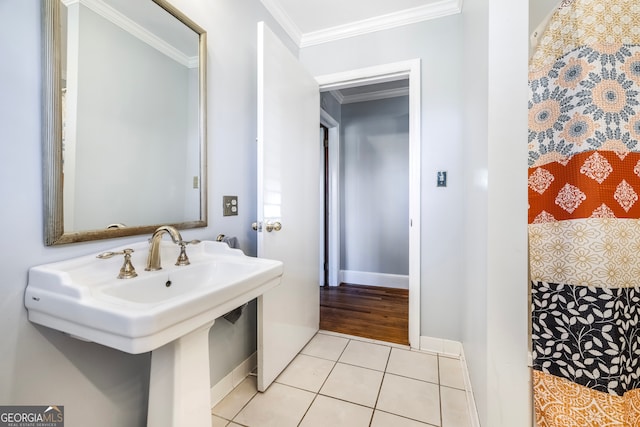 bathroom featuring tile patterned flooring, a sink, baseboards, and ornamental molding