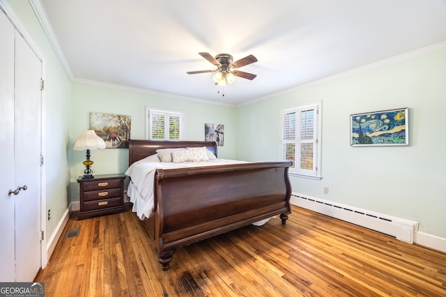 bedroom with visible vents, ornamental molding, a ceiling fan, a baseboard heating unit, and hardwood / wood-style floors