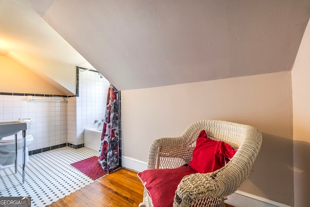 living area with lofted ceiling, a textured ceiling, tile walls, and wood finished floors