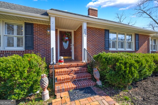 property entrance featuring brick siding and a chimney