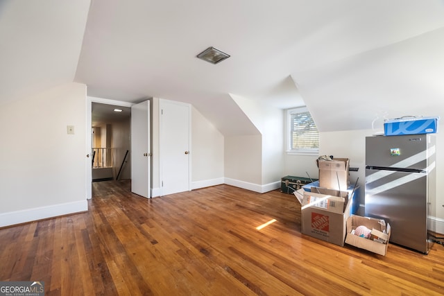 bonus room with hardwood / wood-style floors, lofted ceiling, and baseboards