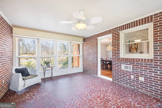 unfurnished sunroom featuring ceiling fan with notable chandelier and a healthy amount of sunlight