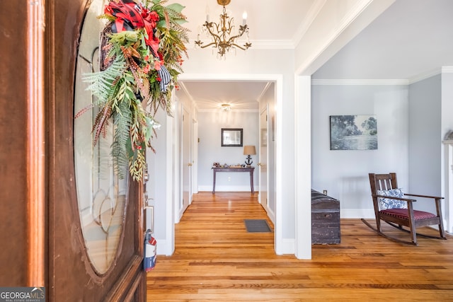 interior space featuring light wood-type flooring, visible vents, ornamental molding, an inviting chandelier, and baseboards