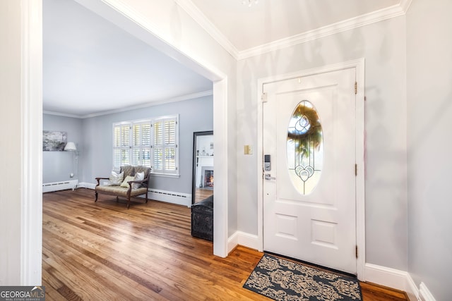 entrance foyer with wood finished floors, baseboards, baseboard heating, and ornamental molding