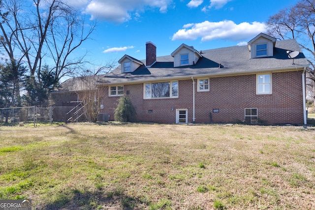 rear view of house with brick siding, fence, a chimney, a yard, and a gate