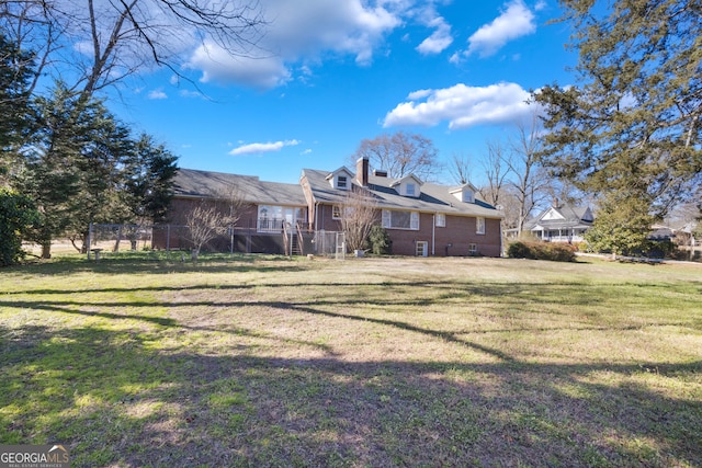 exterior space featuring brick siding, a front yard, and fence