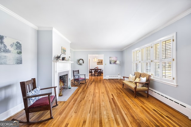 living area with crown molding, a fireplace with flush hearth, light wood finished floors, and a baseboard radiator