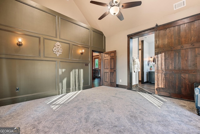 unfurnished bedroom featuring vaulted ceiling, a decorative wall, carpet, and visible vents