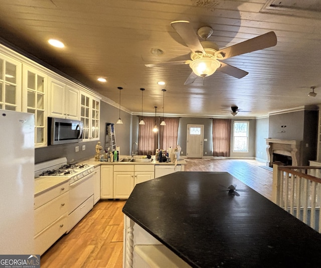 kitchen with open floor plan, a peninsula, light wood-style floors, white appliances, and a sink