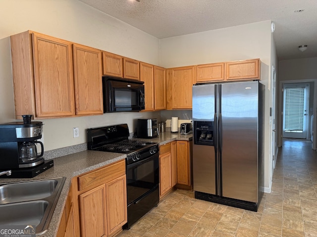 kitchen with dark countertops, a textured ceiling, black appliances, and a sink