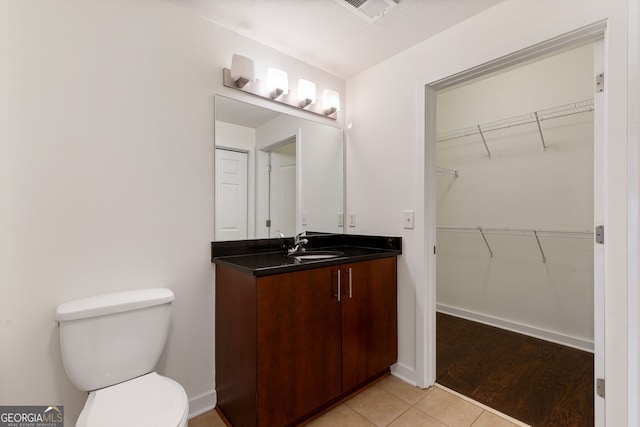 bathroom with vanity, visible vents, tile patterned flooring, a walk in closet, and toilet