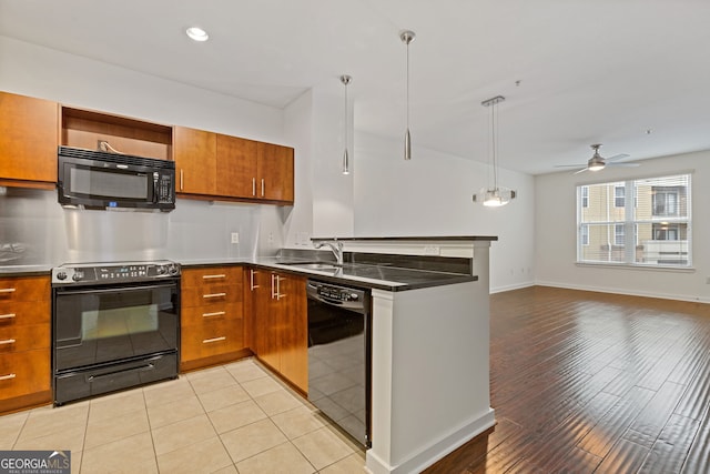 kitchen with brown cabinets, black appliances, a sink, open floor plan, and a peninsula