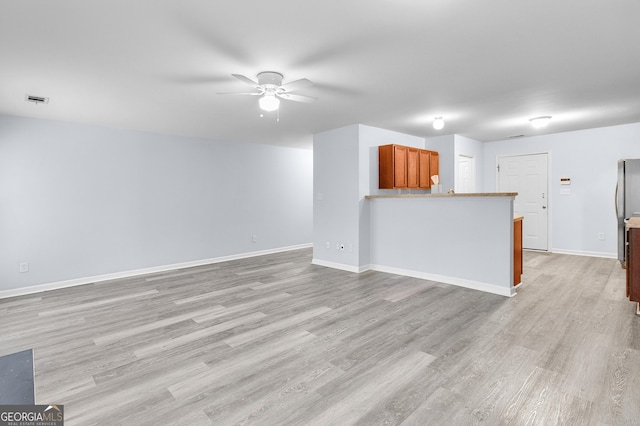 unfurnished living room featuring visible vents, baseboards, light wood-style floors, and a ceiling fan