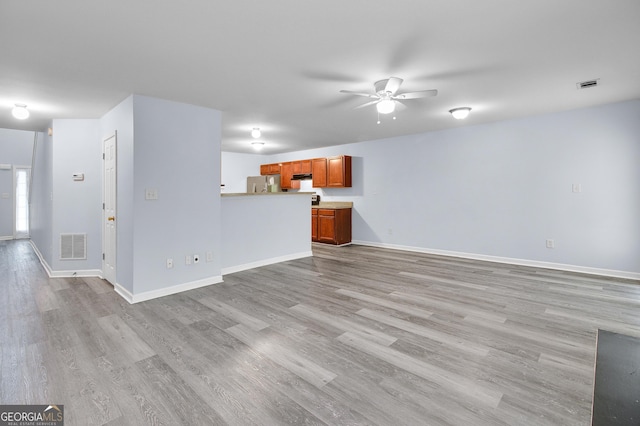 unfurnished living room featuring visible vents, light wood-style flooring, baseboards, and ceiling fan