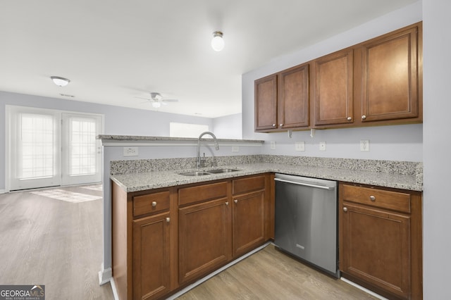 kitchen with light wood-type flooring, a sink, a peninsula, light stone countertops, and dishwasher