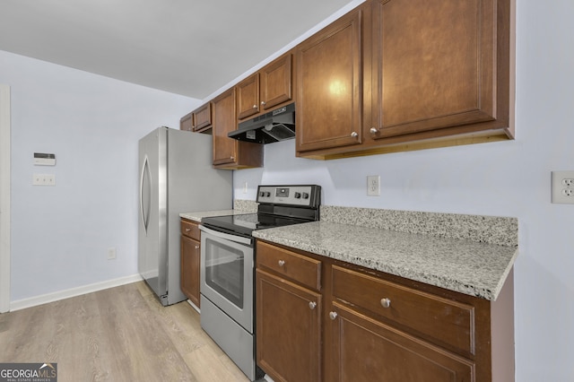 kitchen with baseboards, under cabinet range hood, brown cabinets, appliances with stainless steel finishes, and light wood-style floors