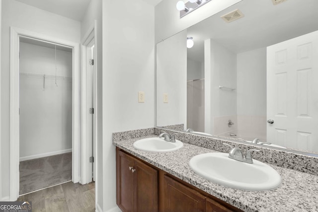 bathroom with a sink, visible vents, a garden tub, and double vanity