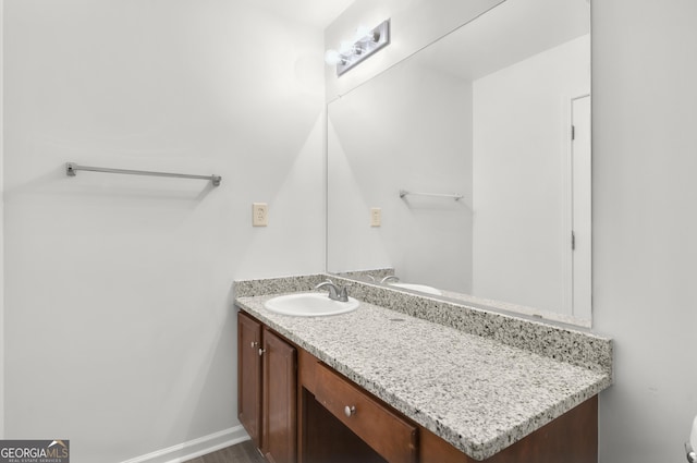 bathroom with toilet, vanity, and baseboards