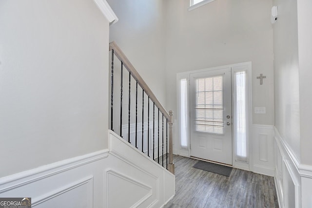 entryway with a wainscoted wall, a healthy amount of sunlight, wood finished floors, and stairs