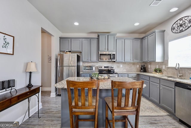 kitchen featuring a sink, stainless steel appliances, gray cabinetry, and decorative backsplash