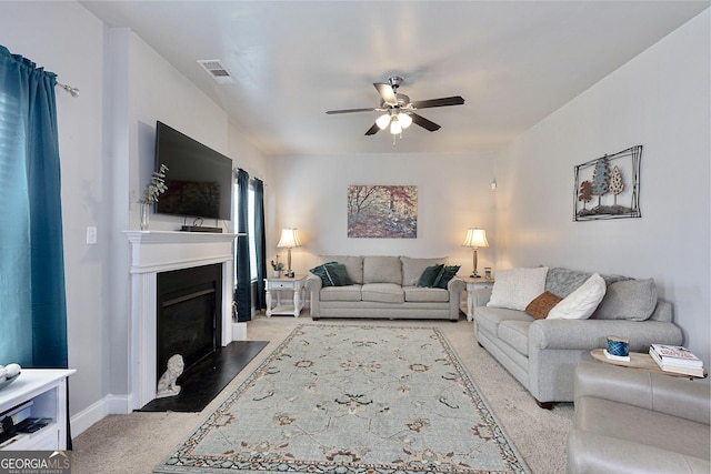 living area with visible vents, a fireplace with flush hearth, baseboards, light colored carpet, and ceiling fan