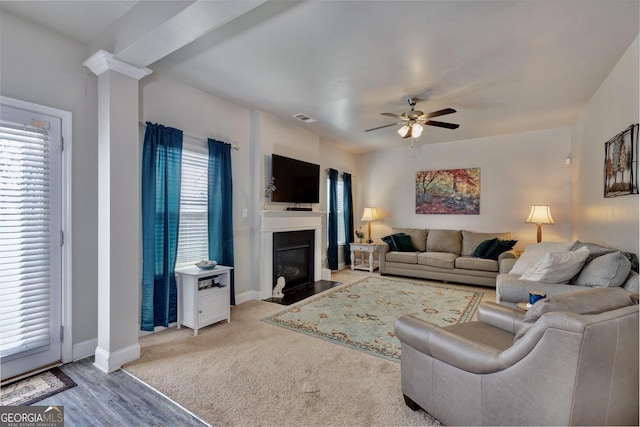 living room with a wealth of natural light, decorative columns, visible vents, and a ceiling fan