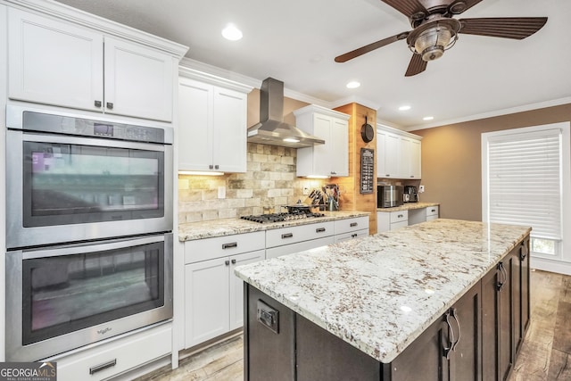 kitchen with backsplash, a center island, crown molding, wall chimney range hood, and stainless steel appliances