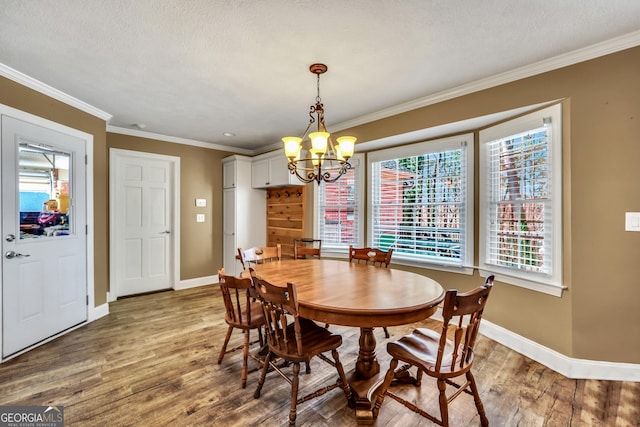 dining area featuring crown molding, baseboards, an inviting chandelier, wood finished floors, and a textured ceiling