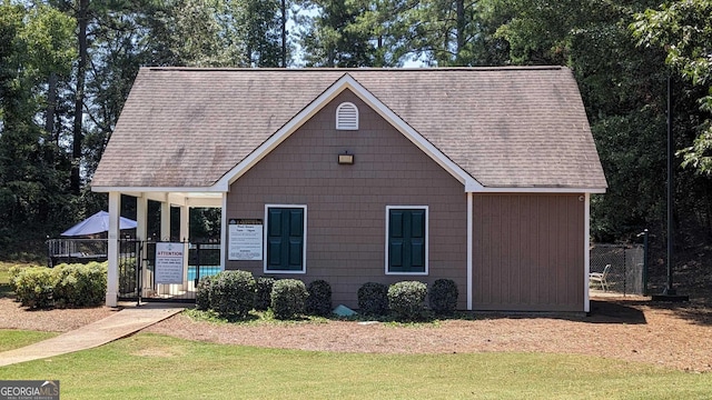 view of front of house featuring a front lawn and a shingled roof