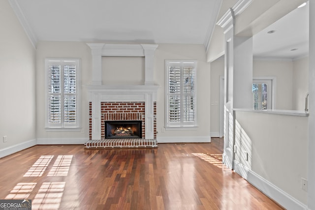 unfurnished living room featuring a fireplace, crown molding, baseboards, and wood finished floors