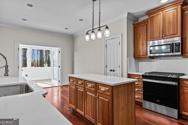kitchen featuring brown cabinetry, ornamental molding, appliances with stainless steel finishes, and a sink