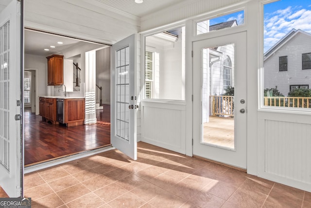 doorway to outside with tile patterned flooring, a sink, french doors, and ornamental molding