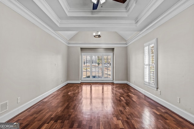 spare room with a raised ceiling, plenty of natural light, wood finished floors, and ornamental molding