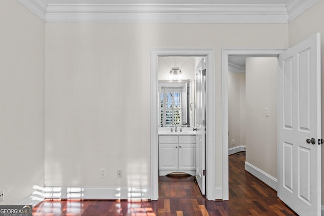 corridor with ornamental molding, dark wood-style floors, baseboards, and a sink