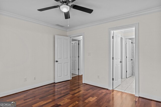 unfurnished bedroom with visible vents, baseboards, wood finished floors, and crown molding