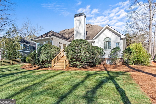 rear view of property featuring a yard, fence, roof with shingles, and a chimney