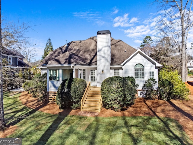rear view of property with a lawn, a chimney, stairs, and roof with shingles