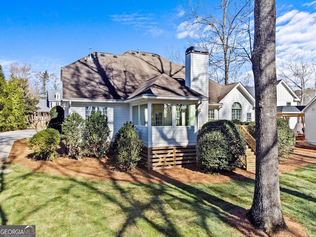 view of front of home featuring a front lawn, roof with shingles, and a chimney