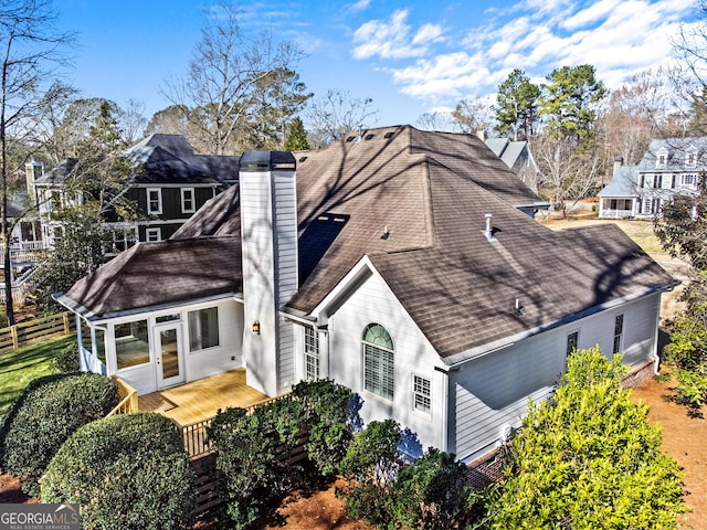view of front of home with a chimney, a deck, and roof with shingles