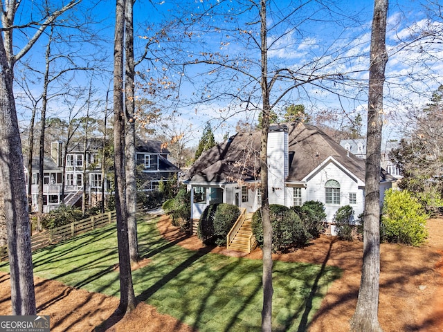 exterior space with a front yard, fence, and a chimney