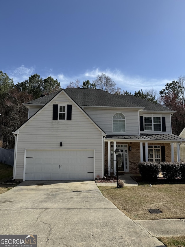 traditional-style house featuring brick siding, concrete driveway, metal roof, a garage, and a standing seam roof